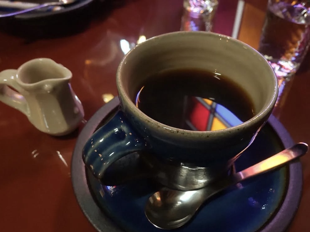 Coffee with the colors of a stained-glass window reflected on the surface, creating a vibrant and artistic effect