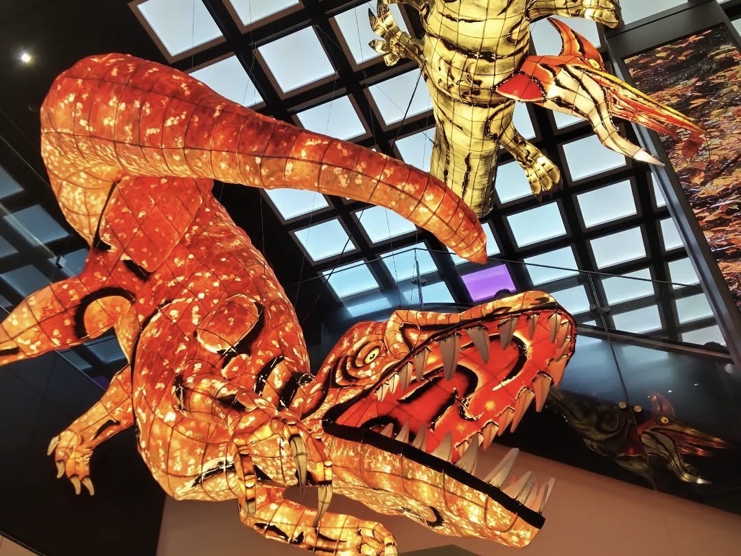 Large paper-crafted dinosaur hanging decoration made of traditional Japanese washi, displayed at Tokyo Station as part of the Northern Japan campaign