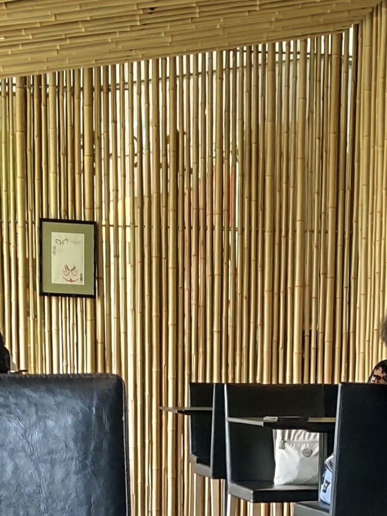 The interior of a Japanese restaurant with walls and a ceiling made of parallel thin bamboo sticks, creating a serene atmosphere