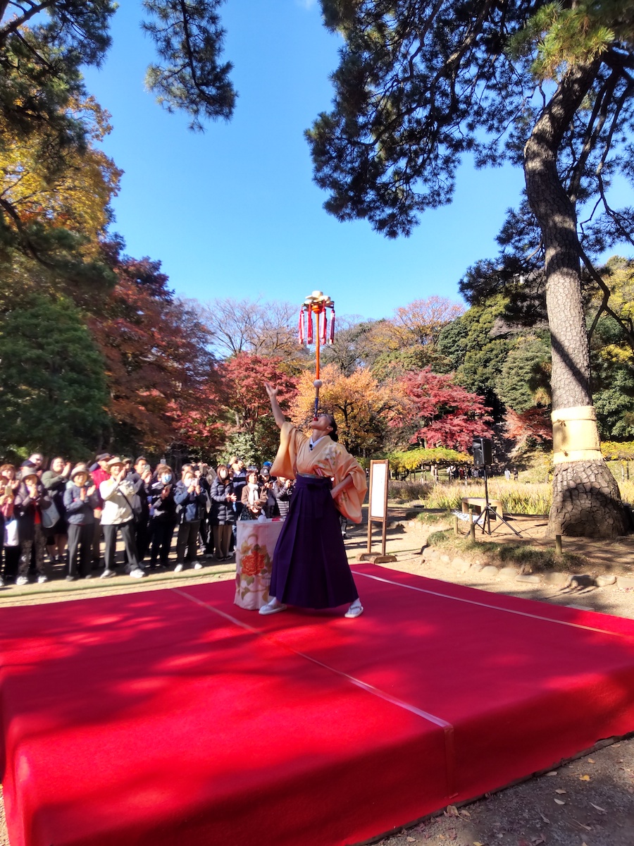 A female performer dances Kagura on a red stage