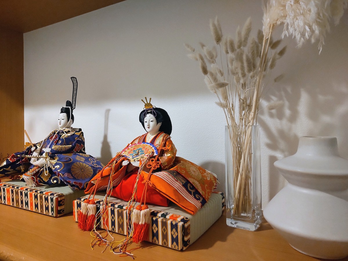 A modern Hina doll display in the entryway, featuring the female doll with dried flowers, gold accents, and a minimalist arrangement