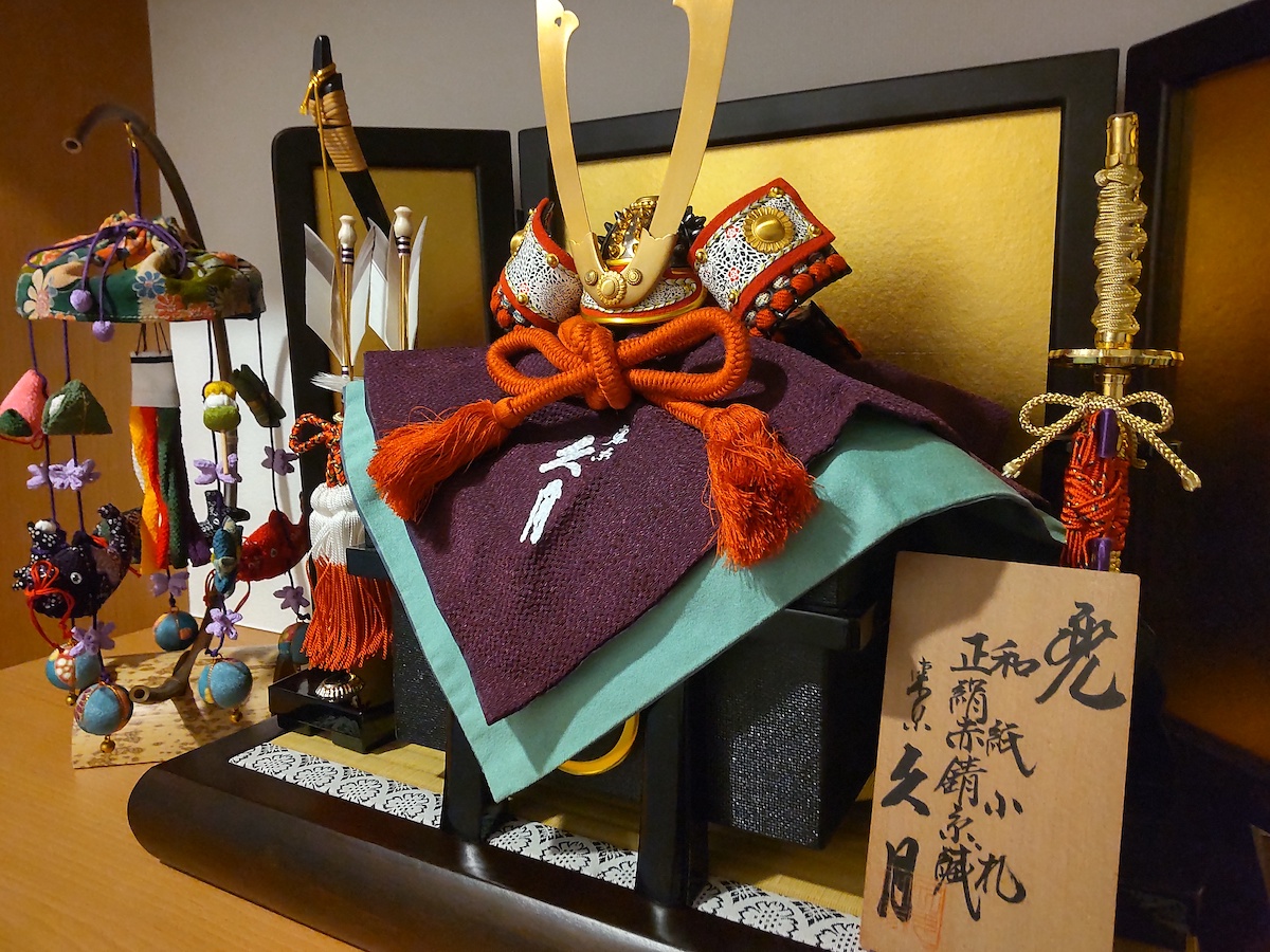 May display featuring a kabuto helmet with orange cords, alongside a traditional hanging ornament