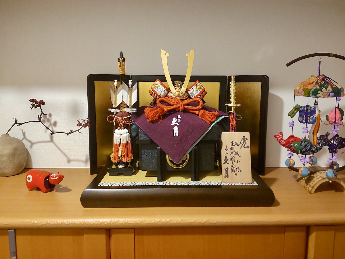 May kabuto display alongside a brown vase holding dried vine with red berries