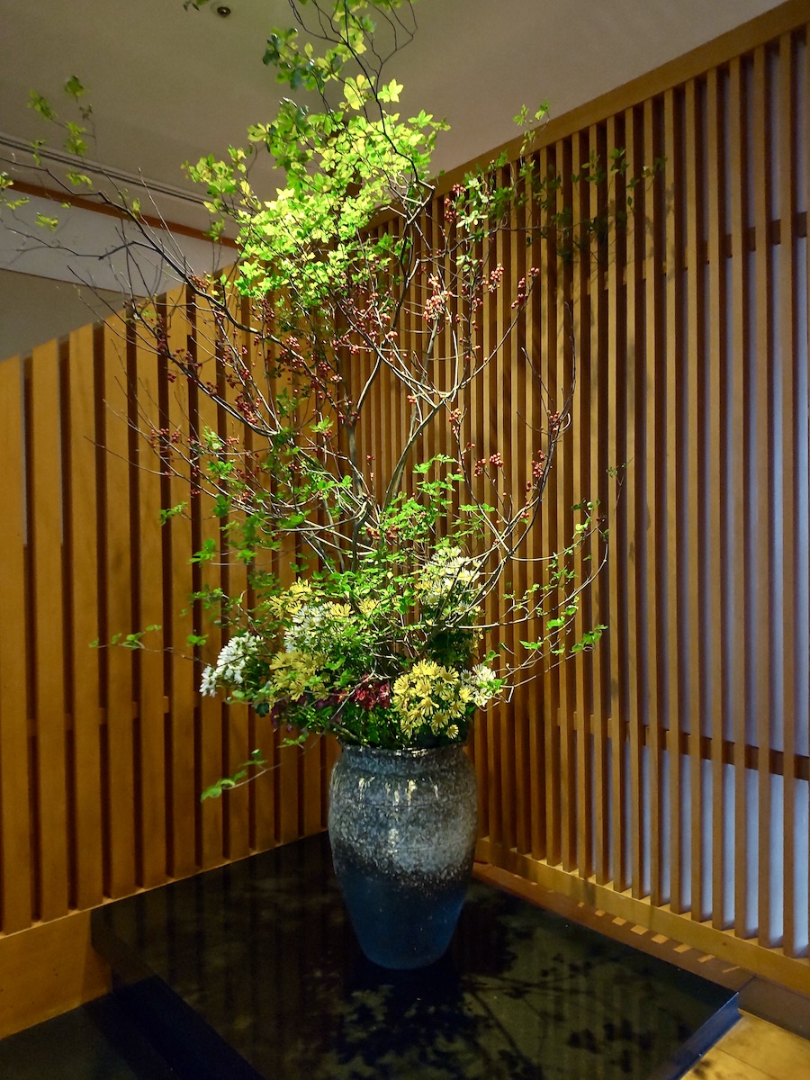 Tall Japanese floral arrangement at the entrance, higher than a person