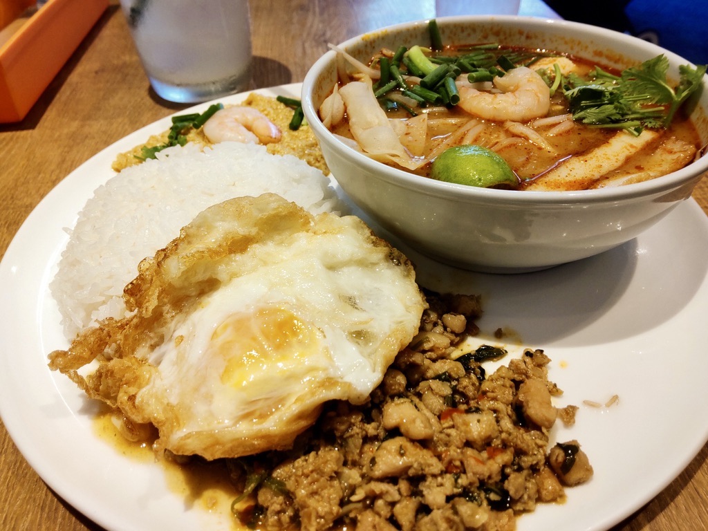 A single plate with gapao rice, egg curry stir-fry, and tom yum goong