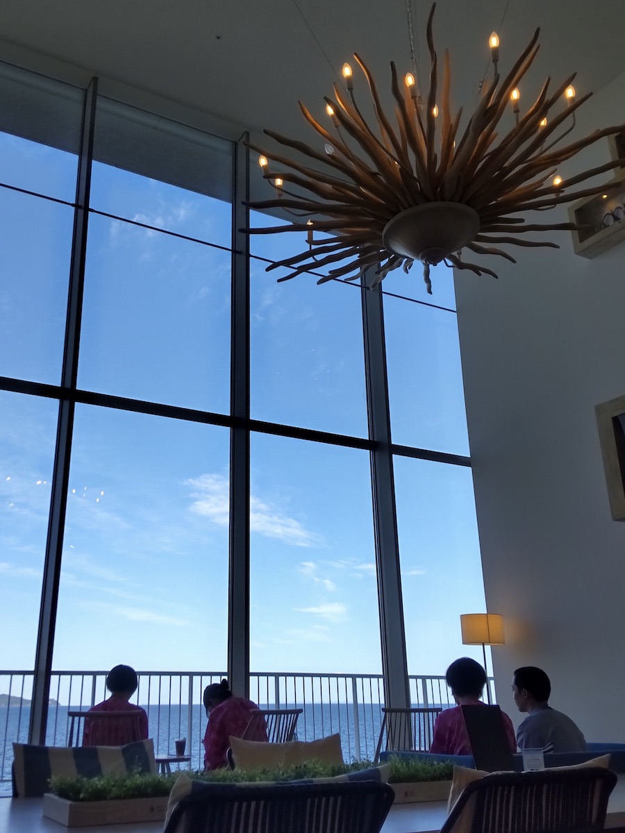 A sun motif hanging from a high ceiling with a sea view
