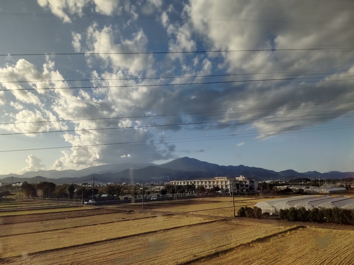 A sunset view over harvested rice fields, houses, and vinyl greenhouses