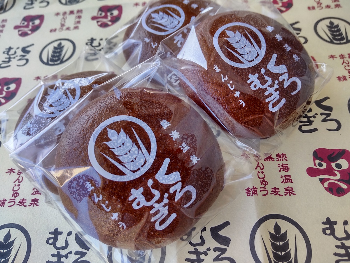 A packaged brown steamed bun on paper with a Tengu illustration