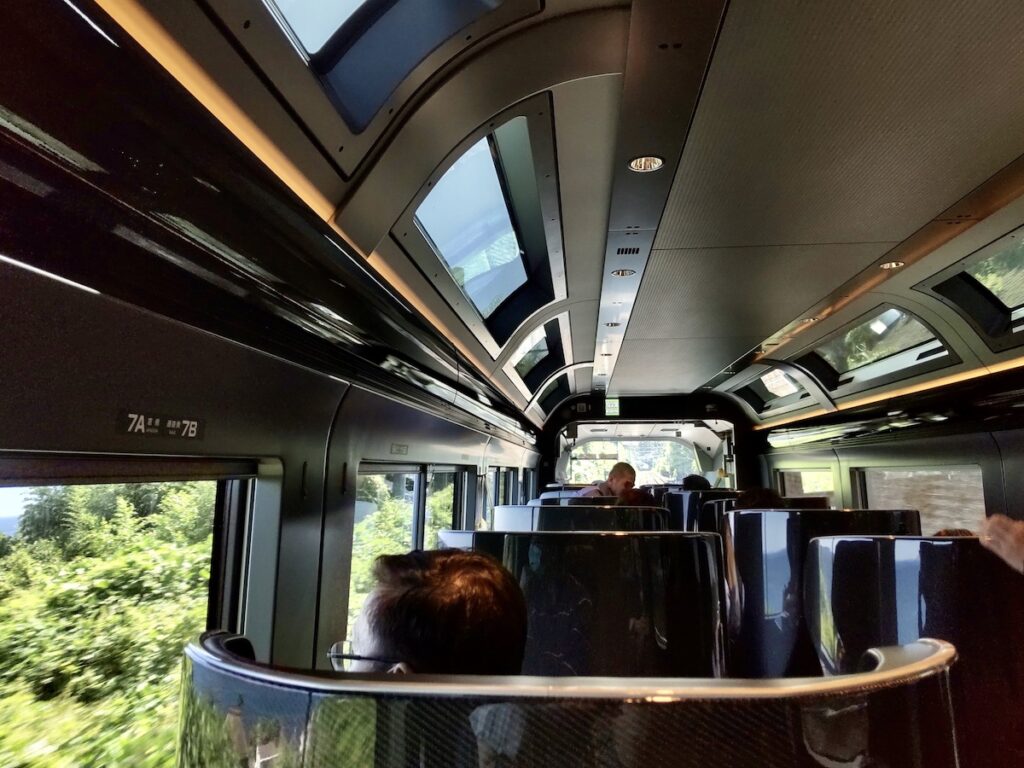A train interior with many windows on the front, sides, and ceiling