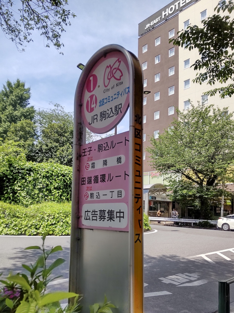 A pink bus stop at a rotary with a hotel in the background