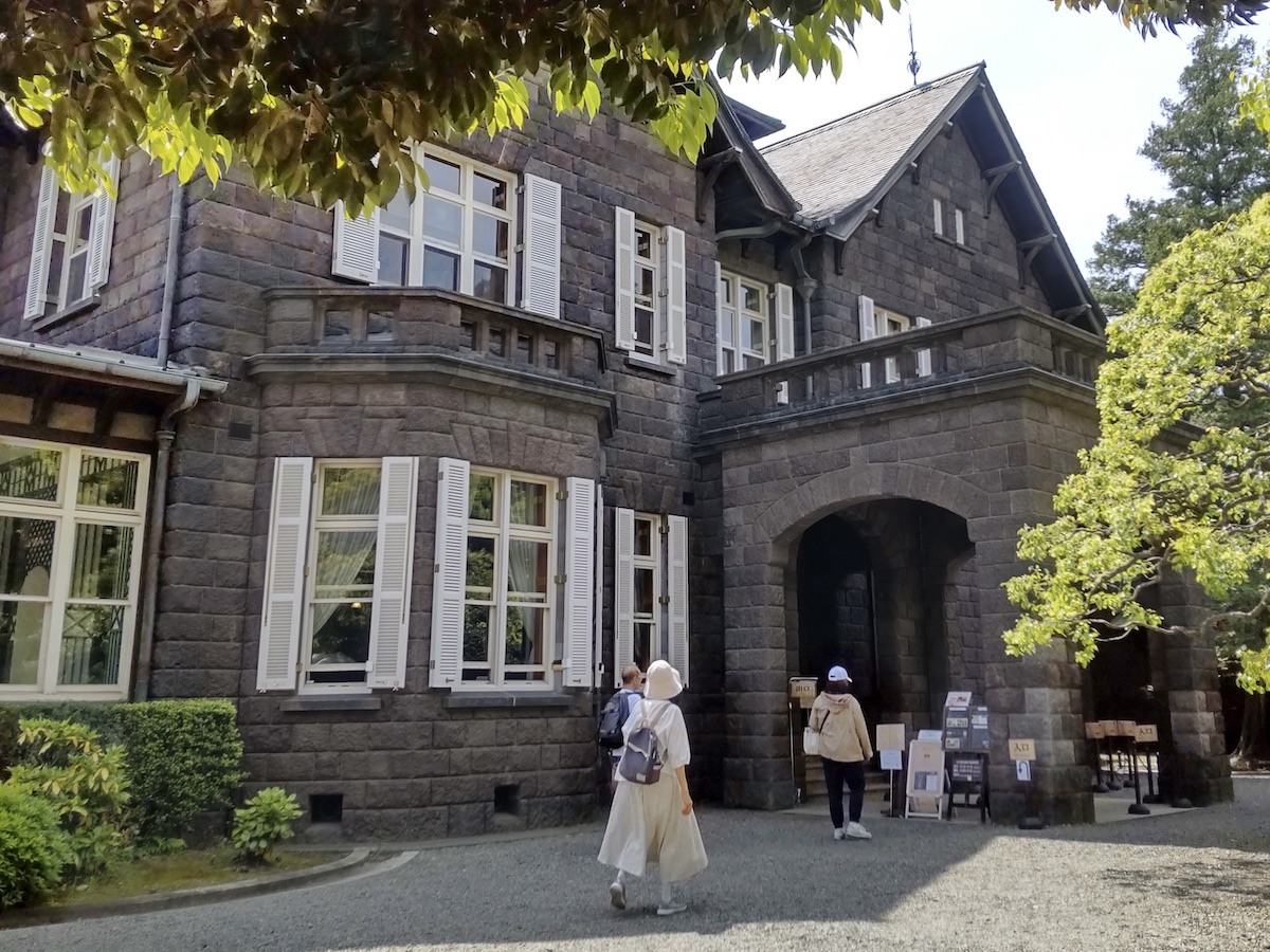 A grand stone Western-style building with people walking in front