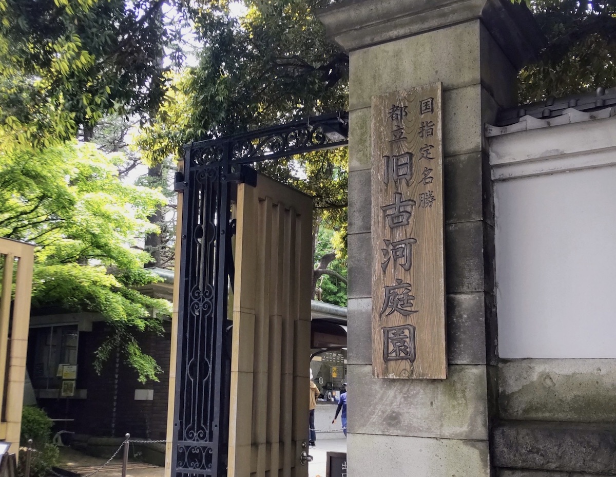 A carved wooden sign hanging beside a large gate entrance