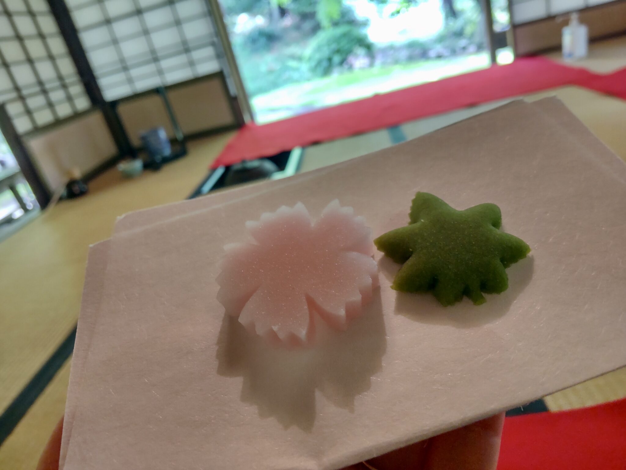 Pink flower-shaped and green maple-shaped dry sweets inside a traditional tearoom