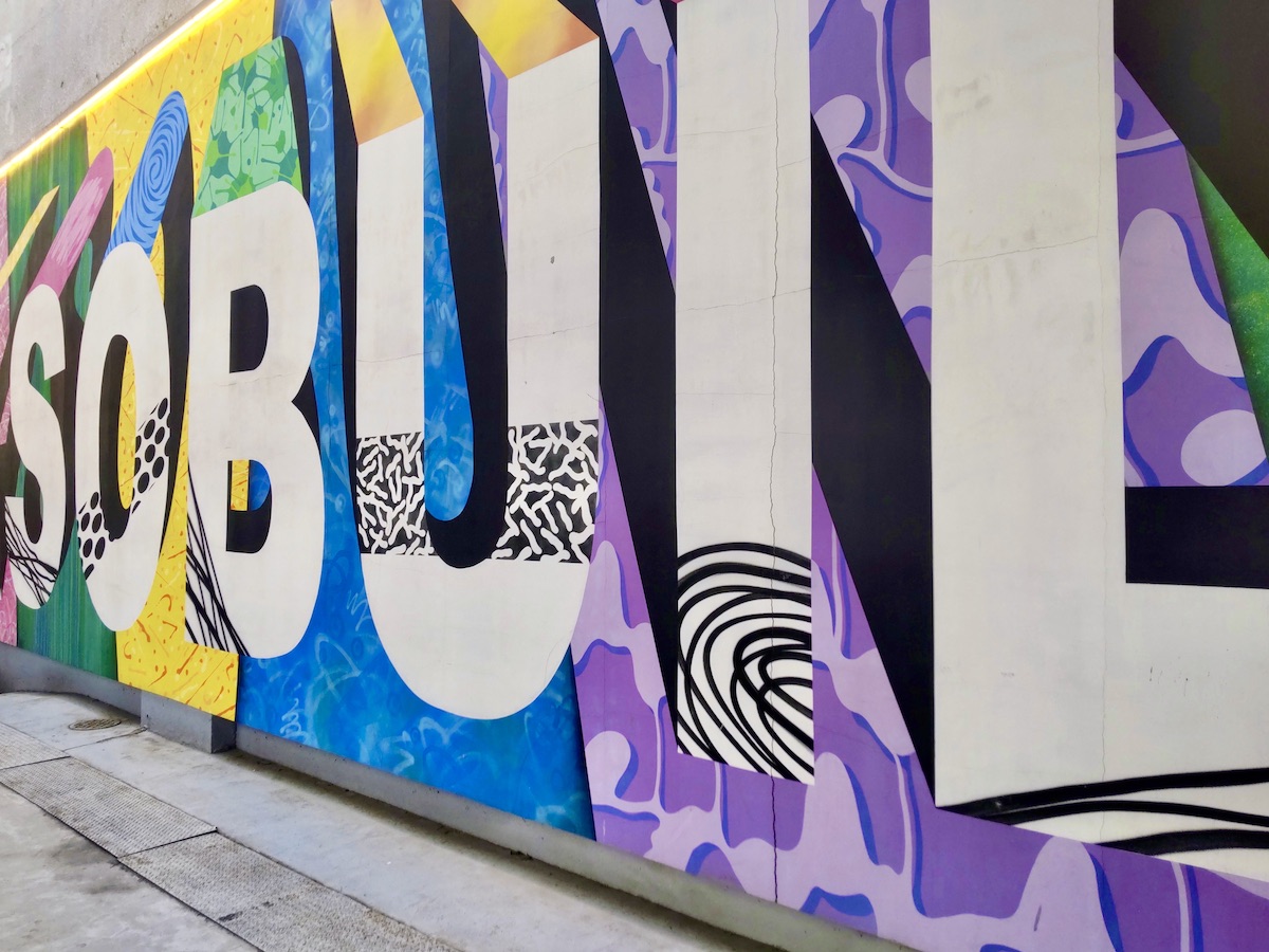 Wall art with the building's name painted in various bright colors