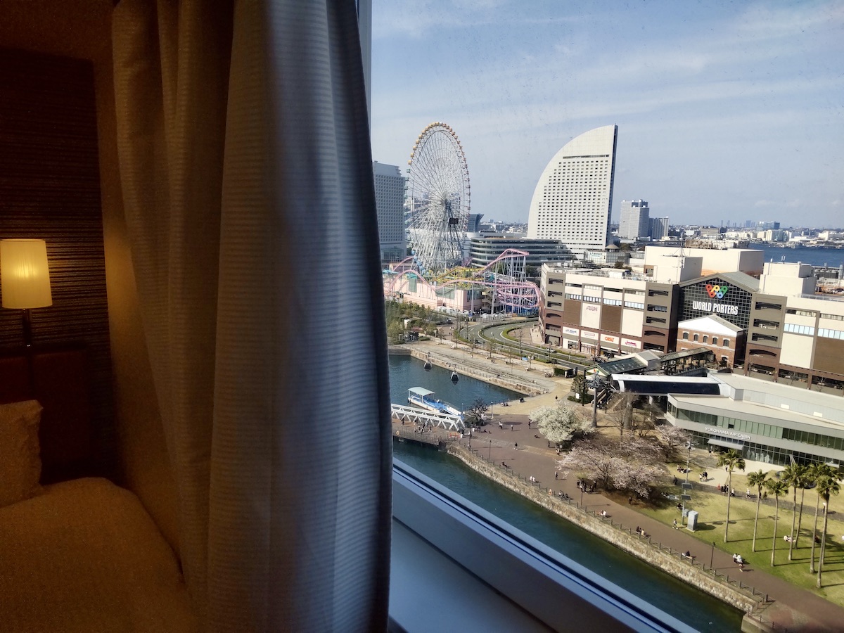 A Ferris wheel and park seen through the opening of hotel curtains