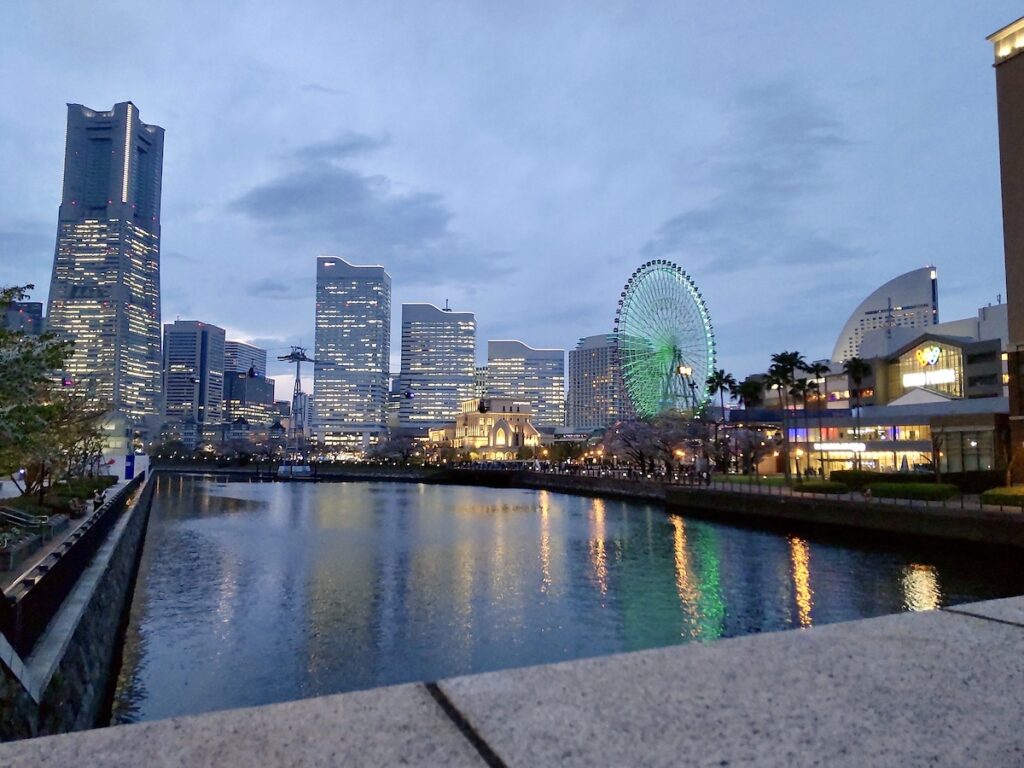 Dusk view of skyscrapers and a Ferris wheel reflecting on the river surface