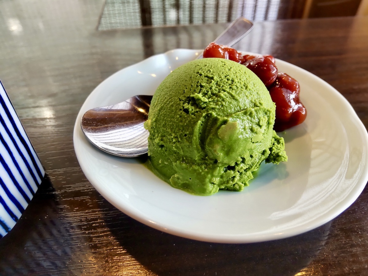 A scoop of matcha ice cream and red beans with green tea