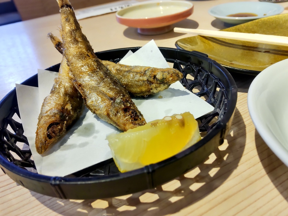Fried small fish served in a basket with fresh lemon