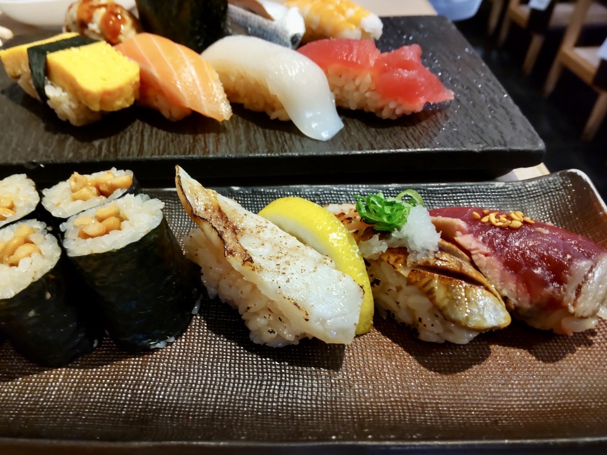Assorted sushi including seared fish and natto rolls with various colorful toppings