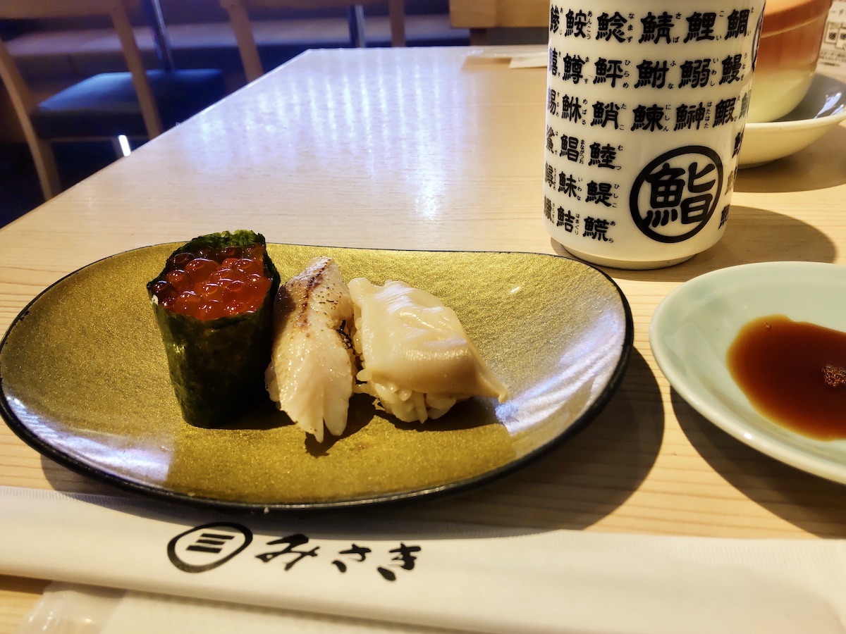 Three pieces of sushi including salmon roe roe on a golden plate