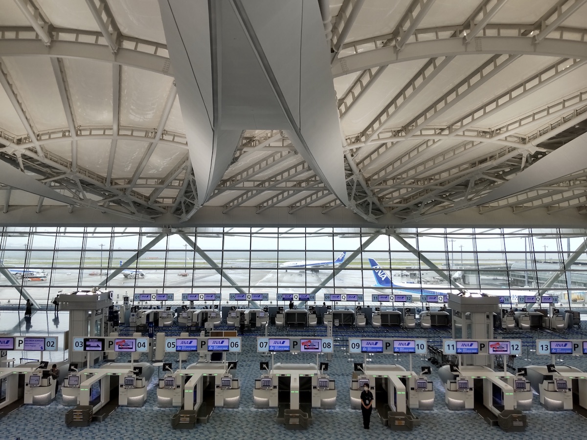 An automated baggage drop area with rows of machines looking out towards an airport apron