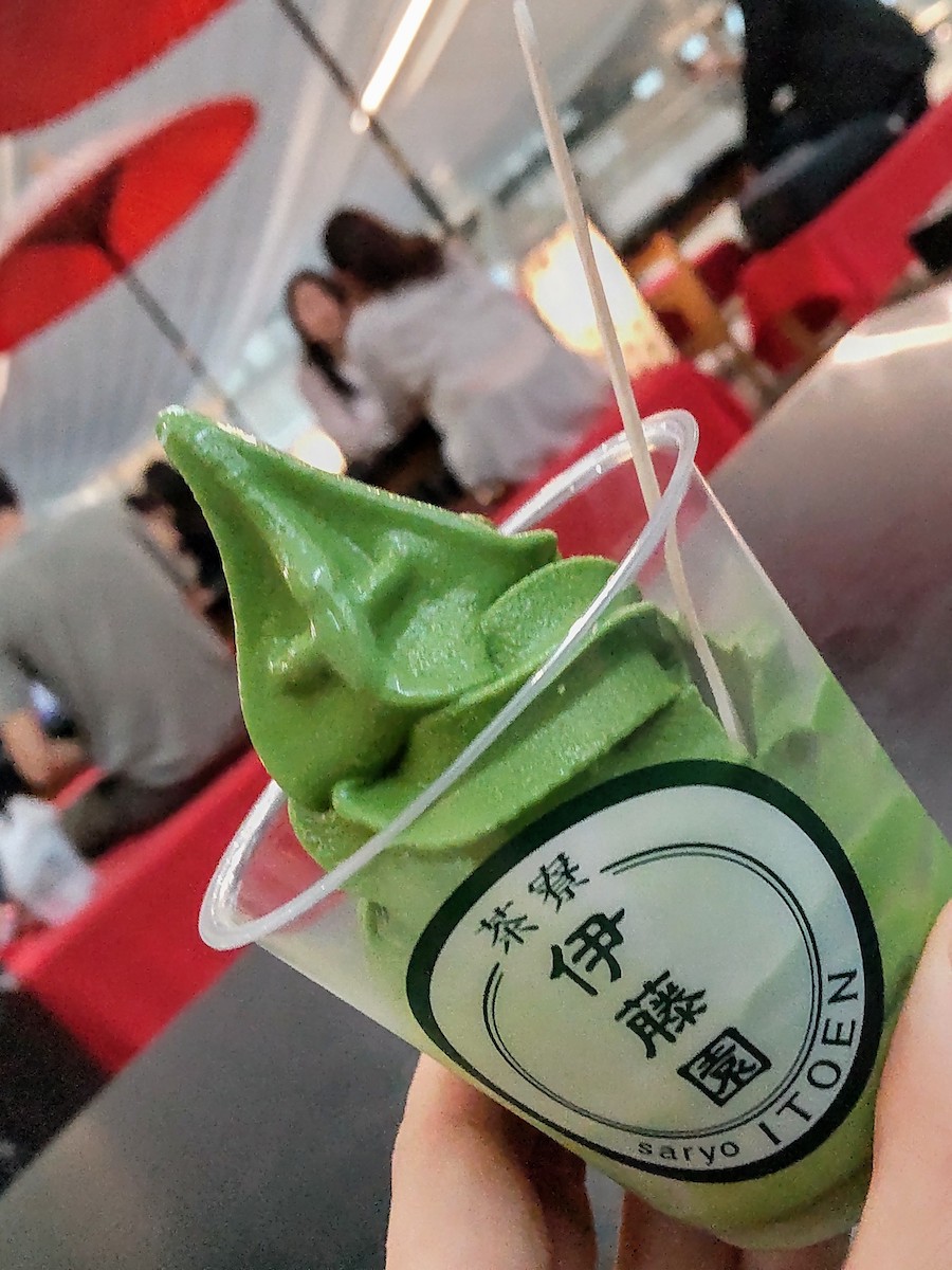 A clear cup with the Itoen logo filled with green matcha soft serve ice cream