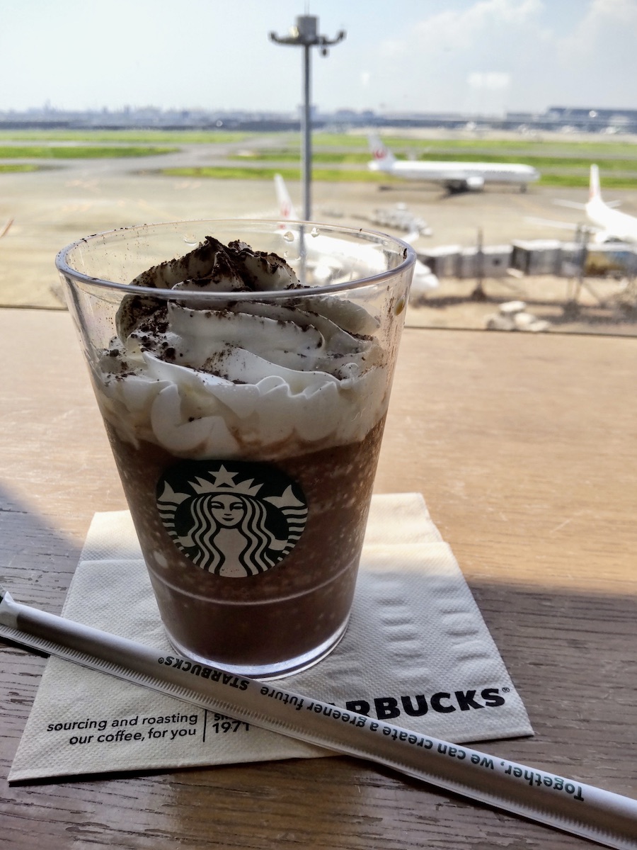 A Starbucks Frappuccino in a cup with an airport apron visible in the background