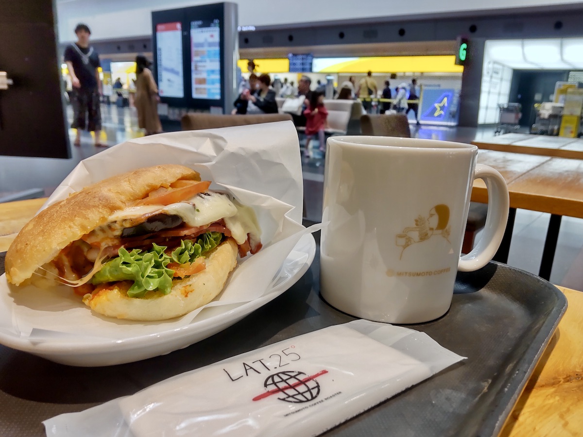A hot sandwich and a mug in the foreground with a check-in counter behind