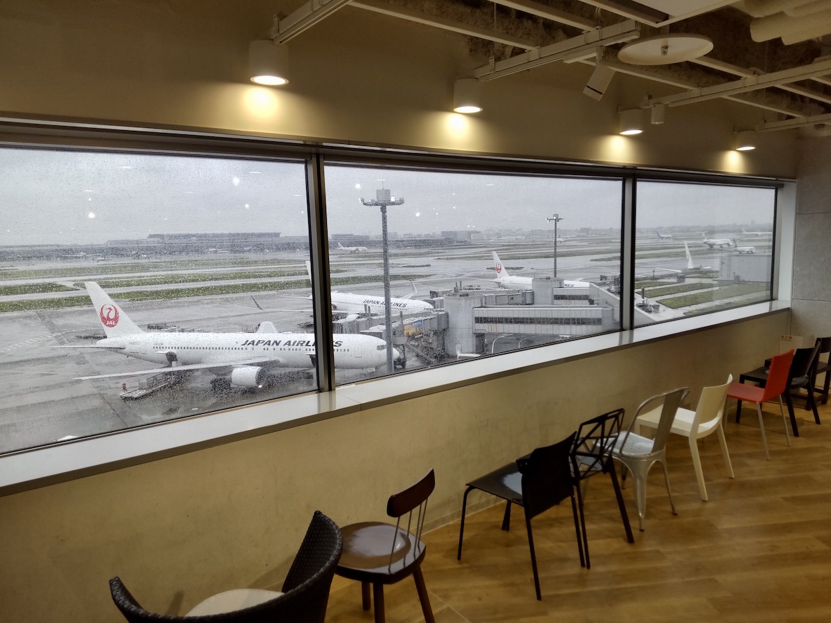 A seating area with various chairs looking out towards an airport apron through windows
