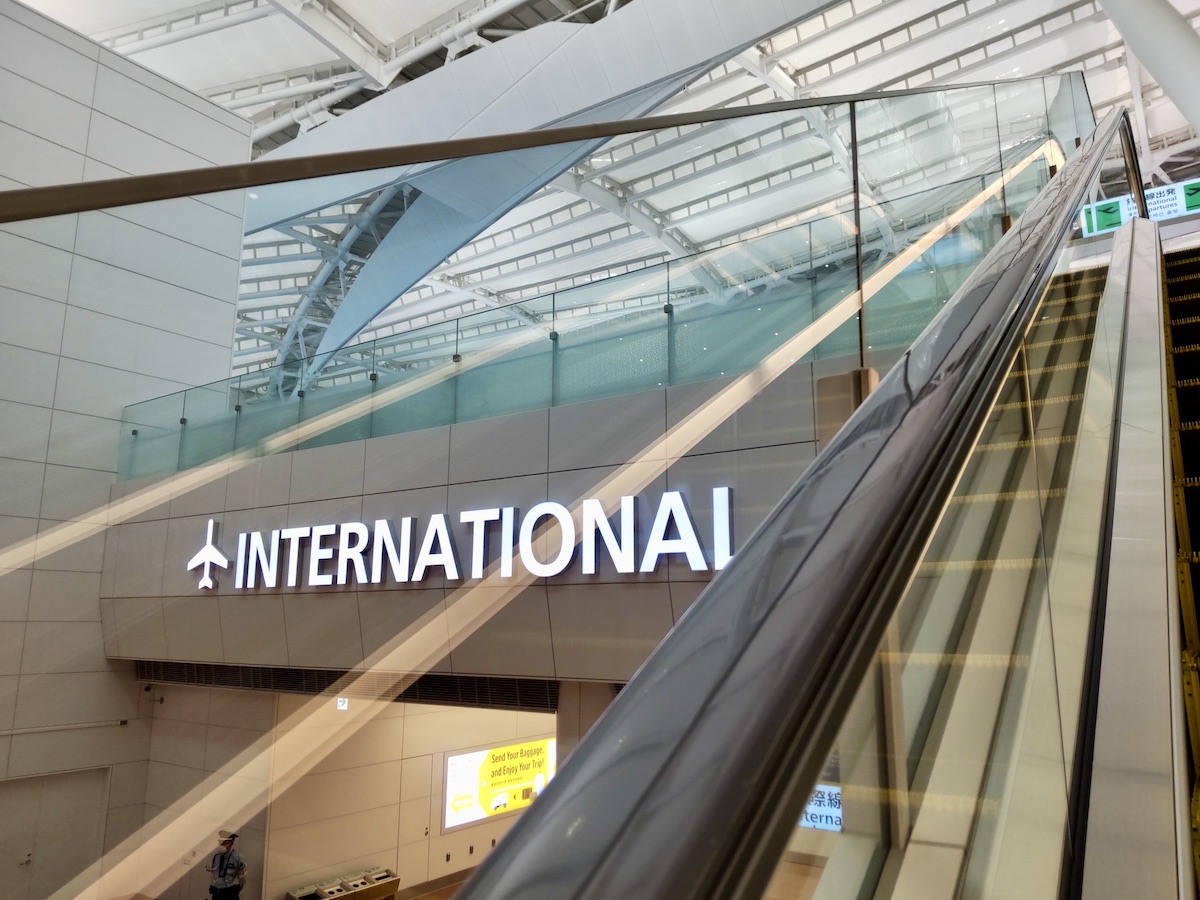 An escalator running alongside a large “International” sign inside an airport terminal