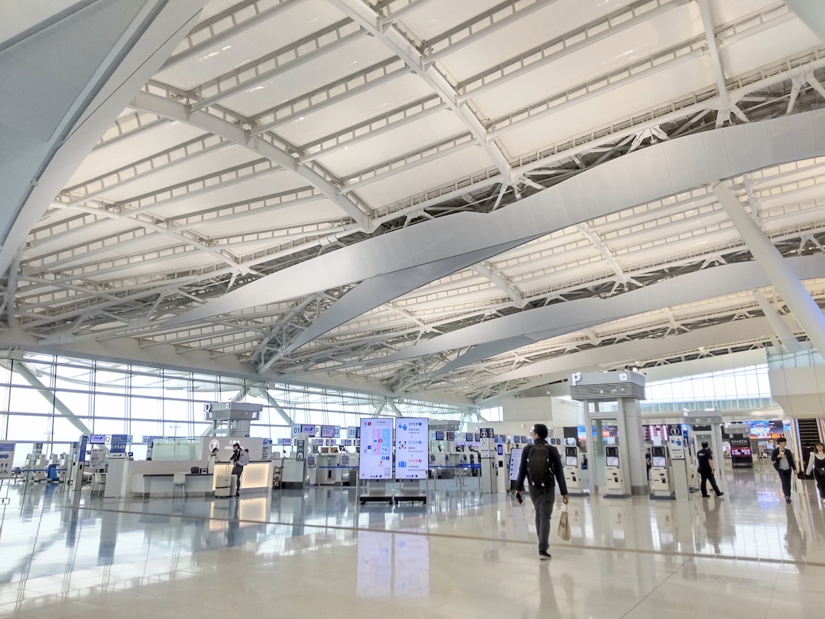 A bright, white airport check-in area filled with rows of multiple service counters