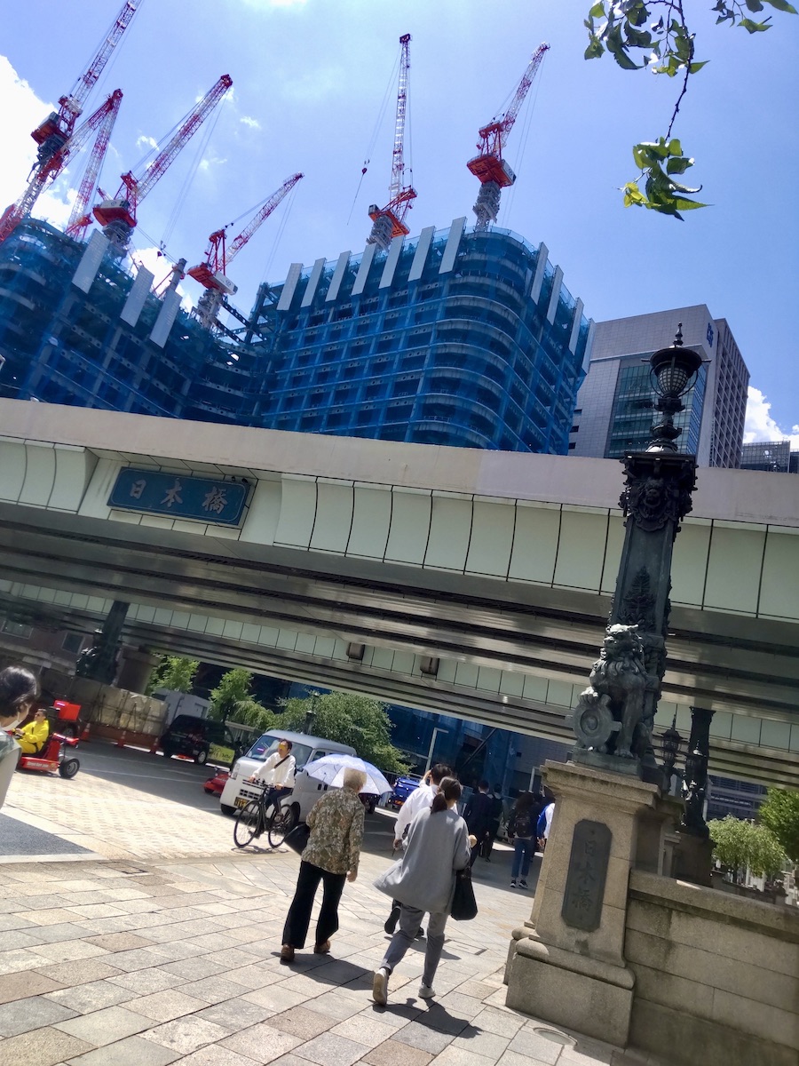 A building under construction visible beyond an expressway featuring the name Nihonbashi