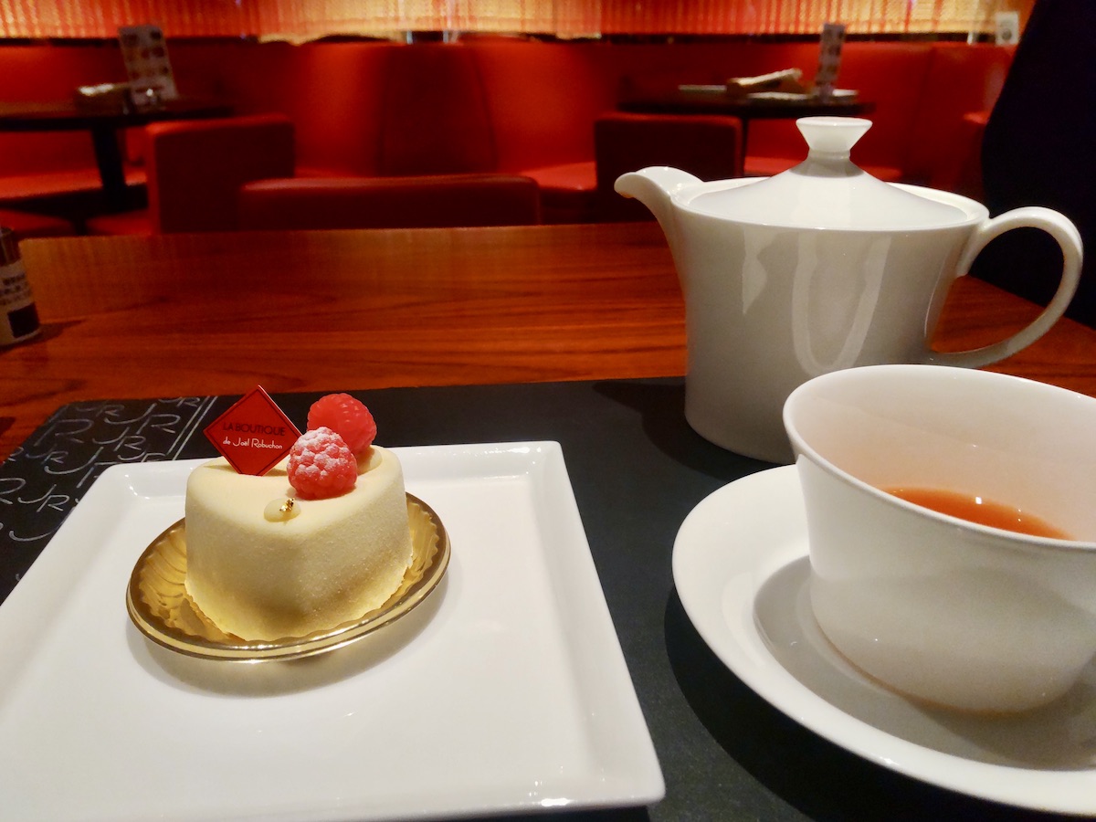 A white heart-shaped cake and tea with a red interior in the background