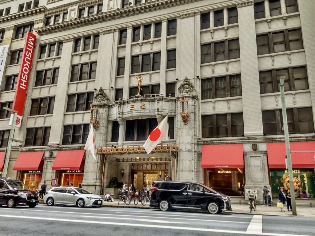 An exterior view of a historic European-style department store building adorned with national flags