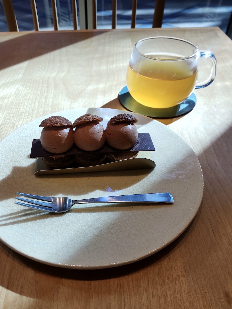 A chocolate cake made of three connected spheres served with a cup of tea