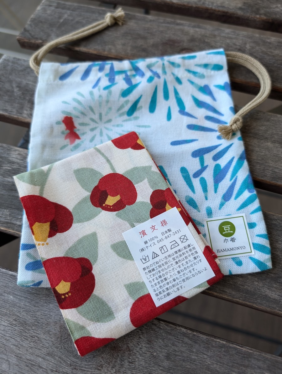 A red floral Japanese handkerchief neatly placed on top of a light blue drawstring pouch
