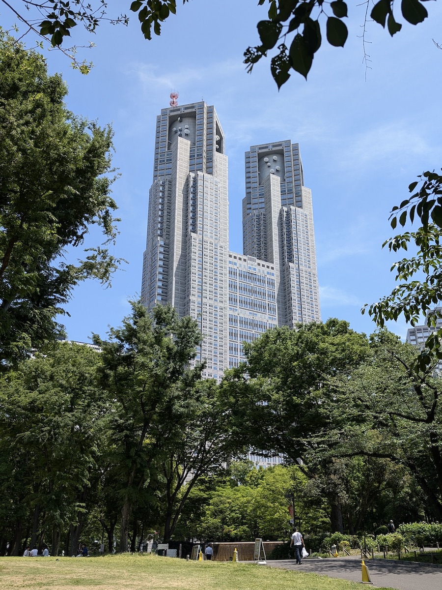 A rectangular twin-tower building rising high above the green trees of a public park