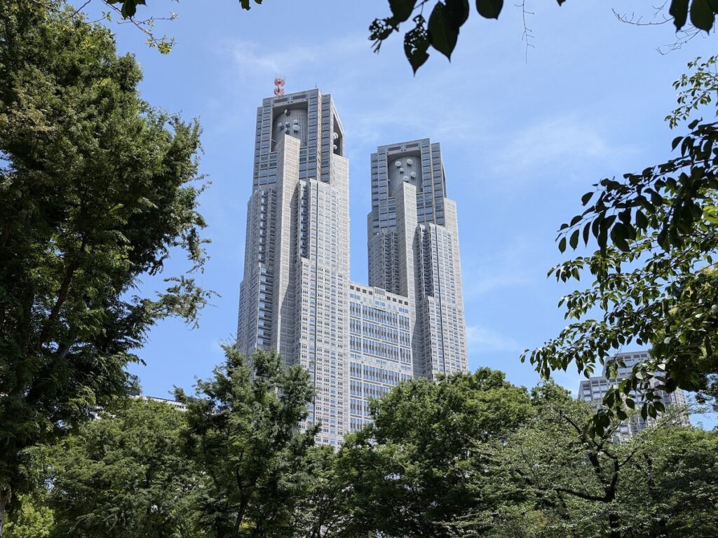 A large building with square twin towers visible through lush green tree branches
