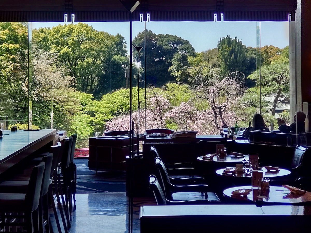 A lounge window overlooking a landscape of greenery and cherry blossoms