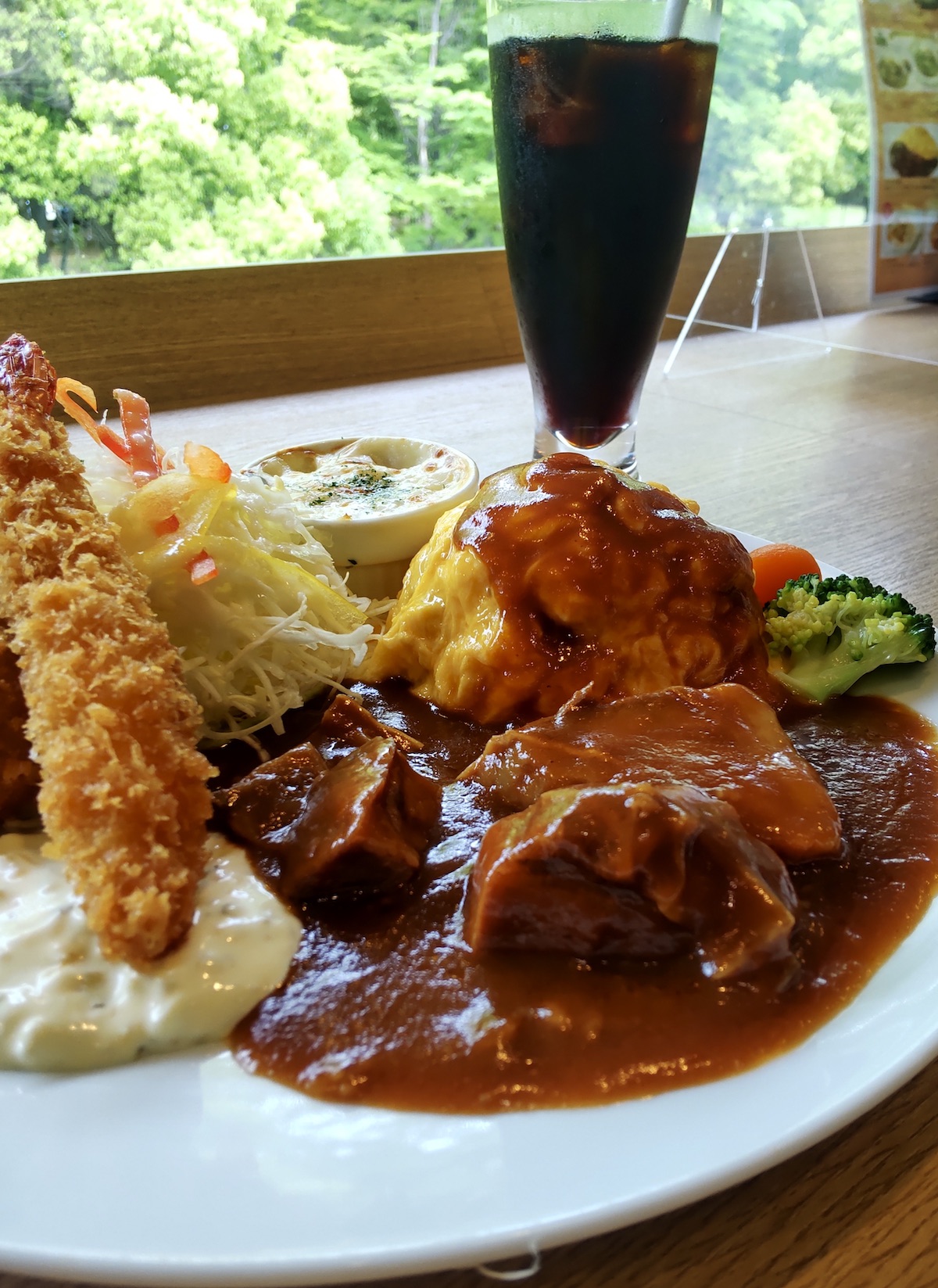 Omelet rice, fried shrimp, and beef stew with greenery background