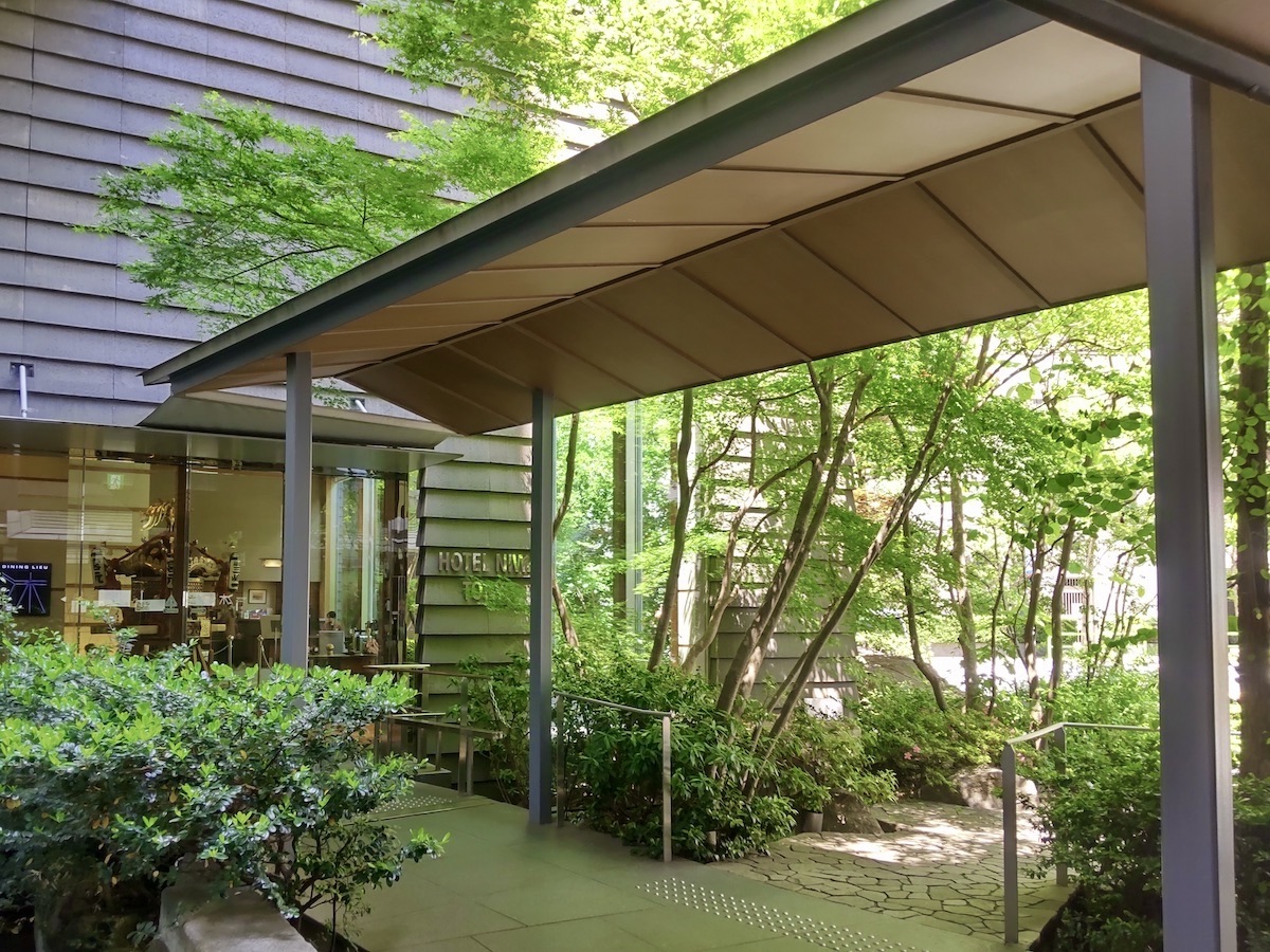 A path leading to a hotel entrance surrounded by fresh greenery