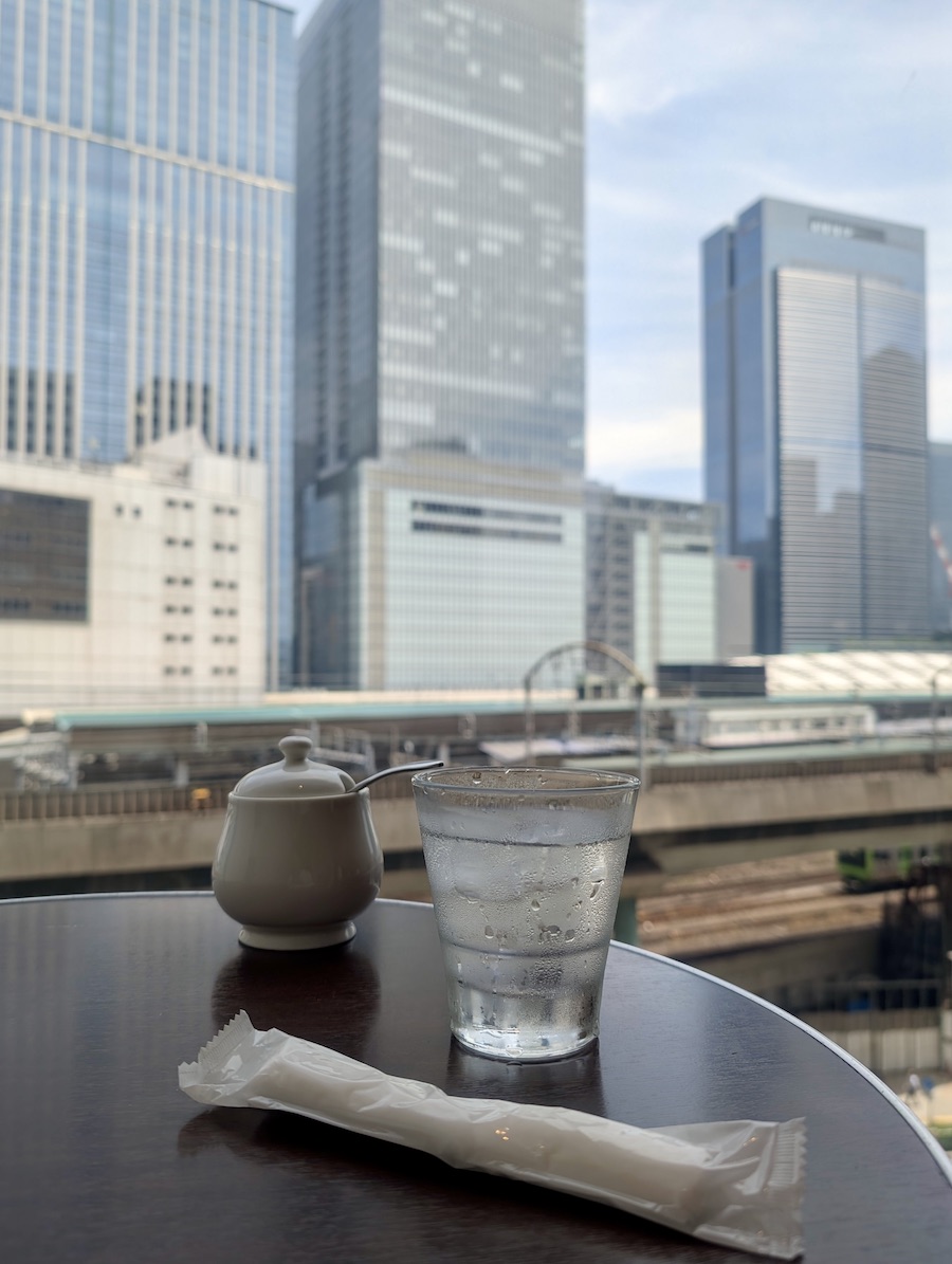 A view from a table showing skyscrapers with a station and trains in the foreground