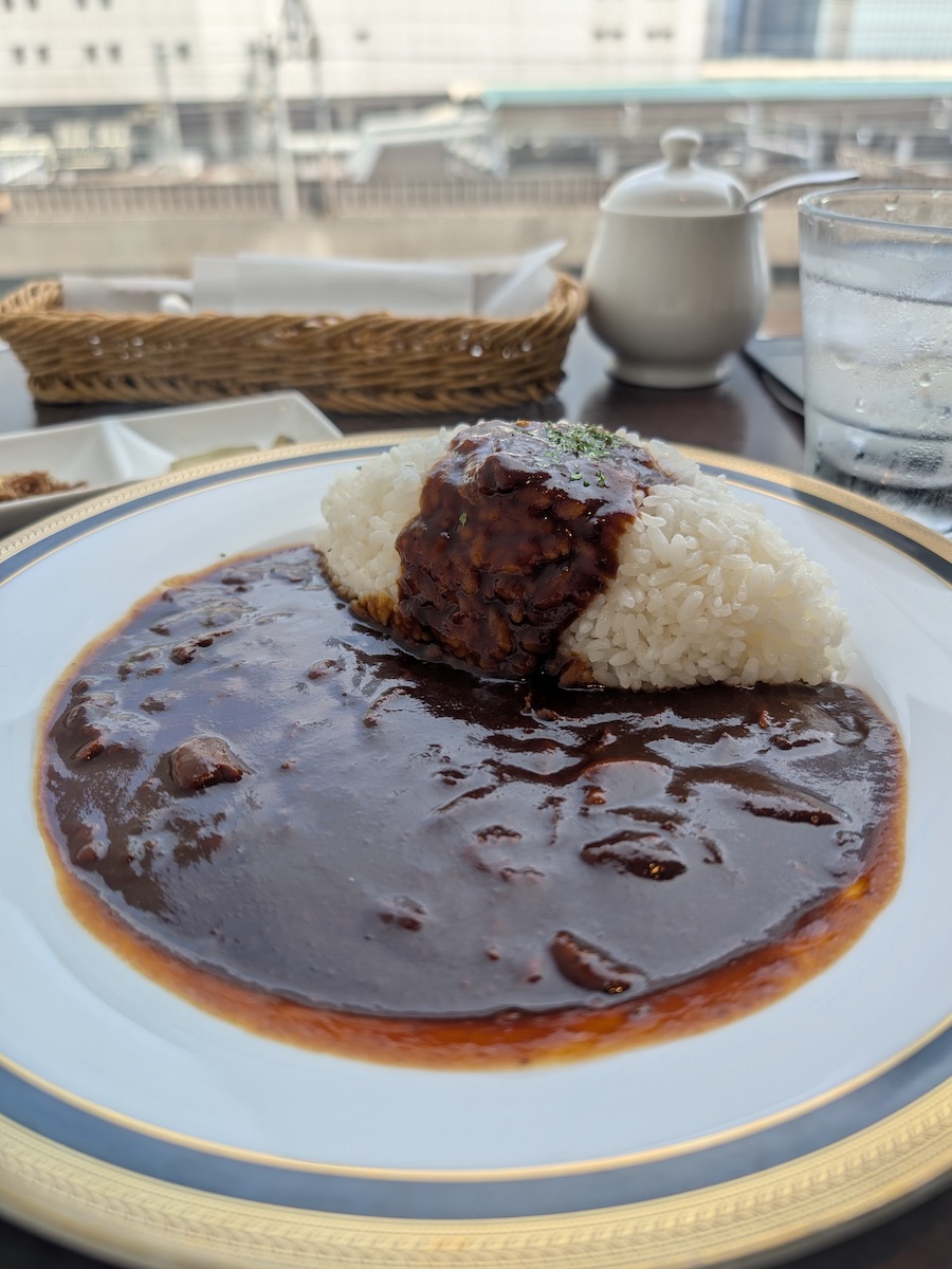 A beautifully shaped serving of rice with brown stew on a gold-rimmed plate