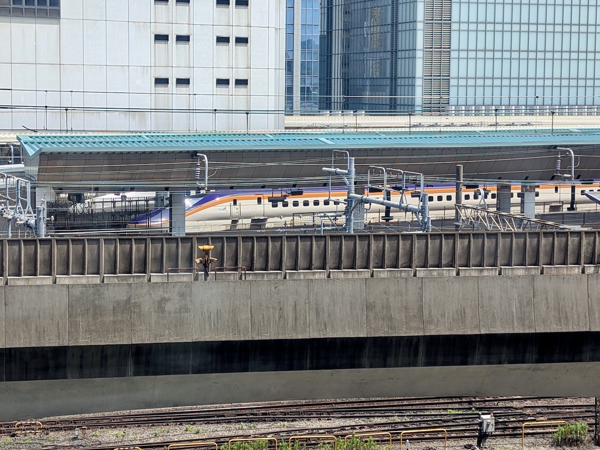 A train with purple and orange lines on a white body stopped at a station