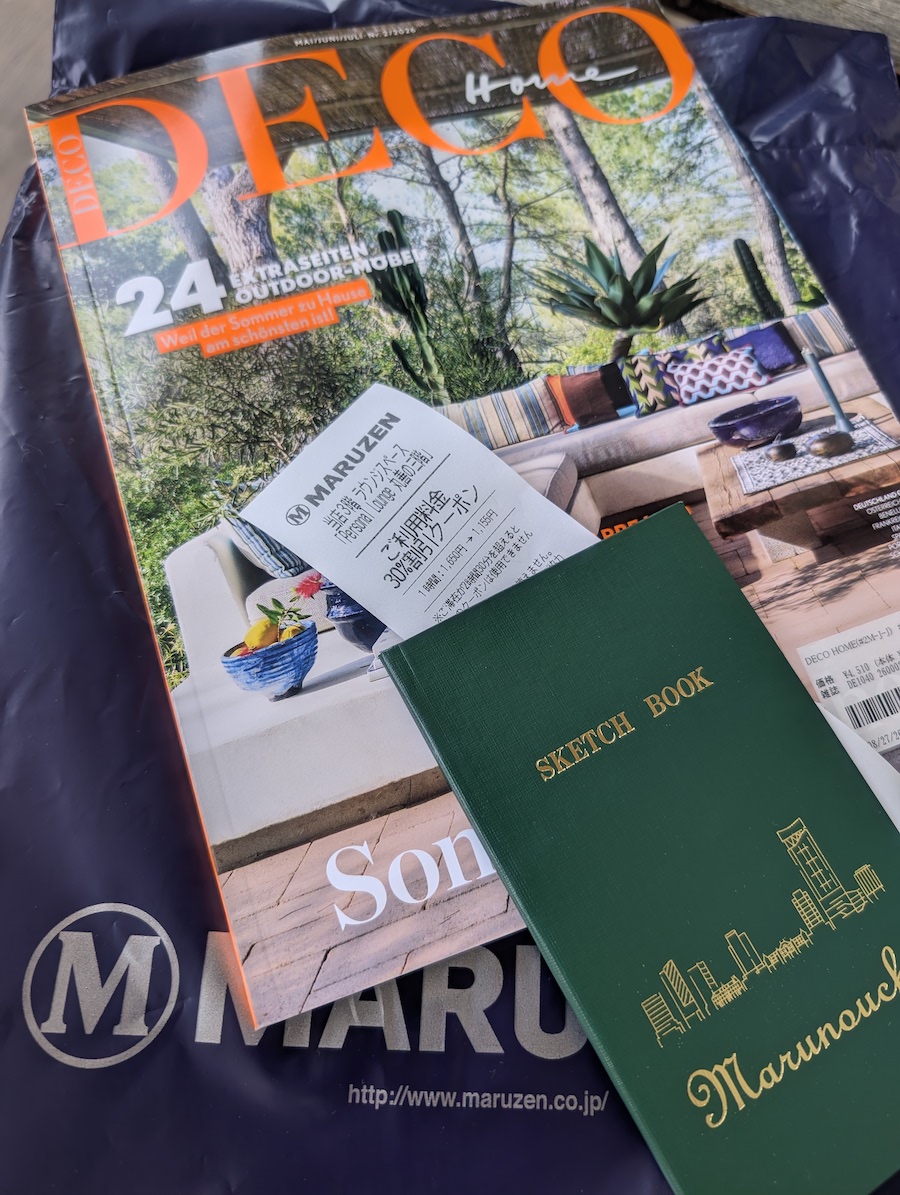 A magazine with an orange title, topped with a notepad and a receipt