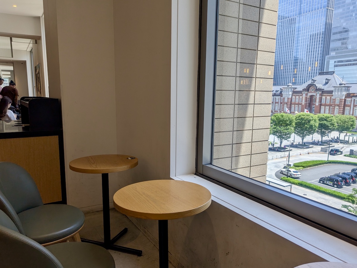 Single-person cafe tables lined up by a window with Tokyo Station visible outside