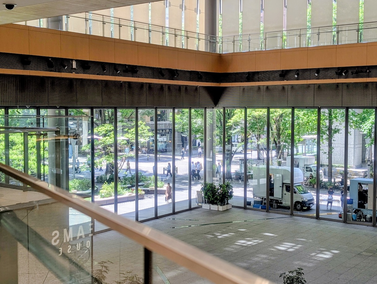 A large open-ceiling lobby with beautiful greenery visible beyond the glass wall