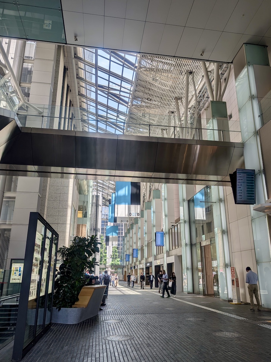 A glass-roofed building walkway lined with hanging banners