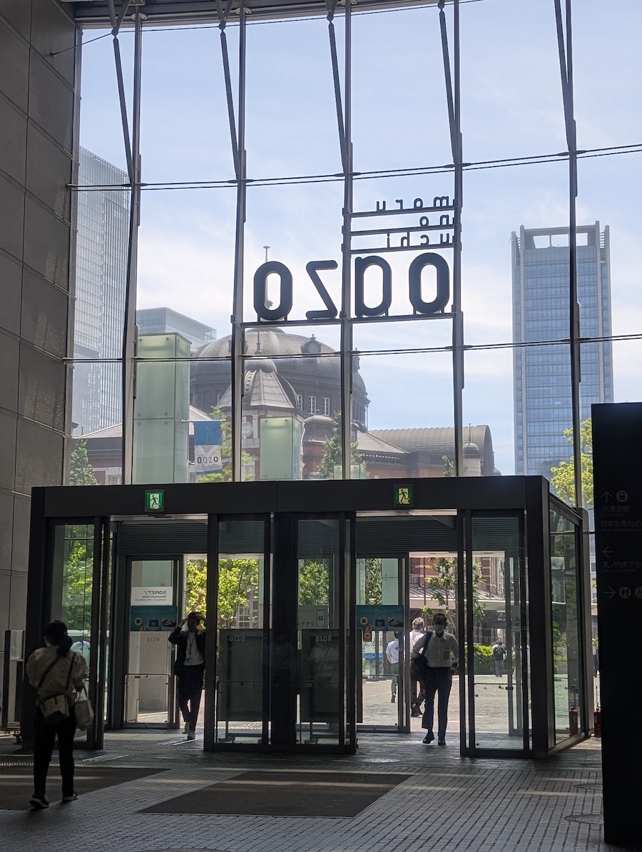 An open-ceiling building entrance with a grand view of Tokyo Station beyond the glass