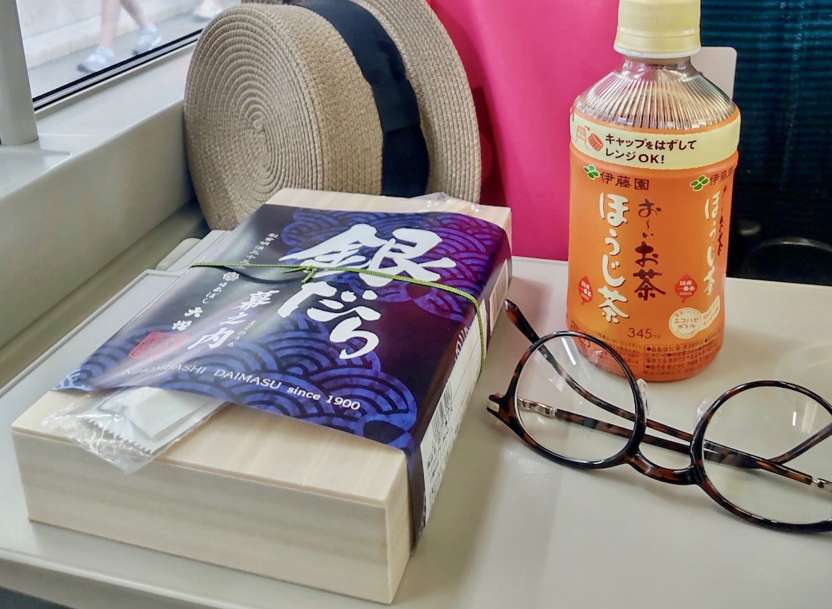 A Japanese train bento box in a blue wrapper on a train seat table